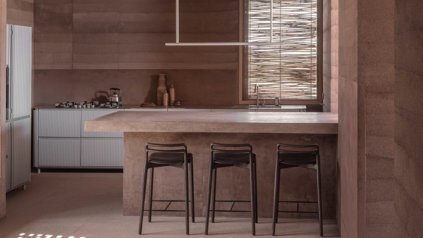 Metallic units in rammed-earth kitchen