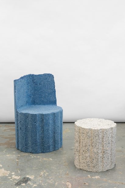 Photograph of two pieces from the collection, including a blue granite-looking armchair and a white granite-looking stool.