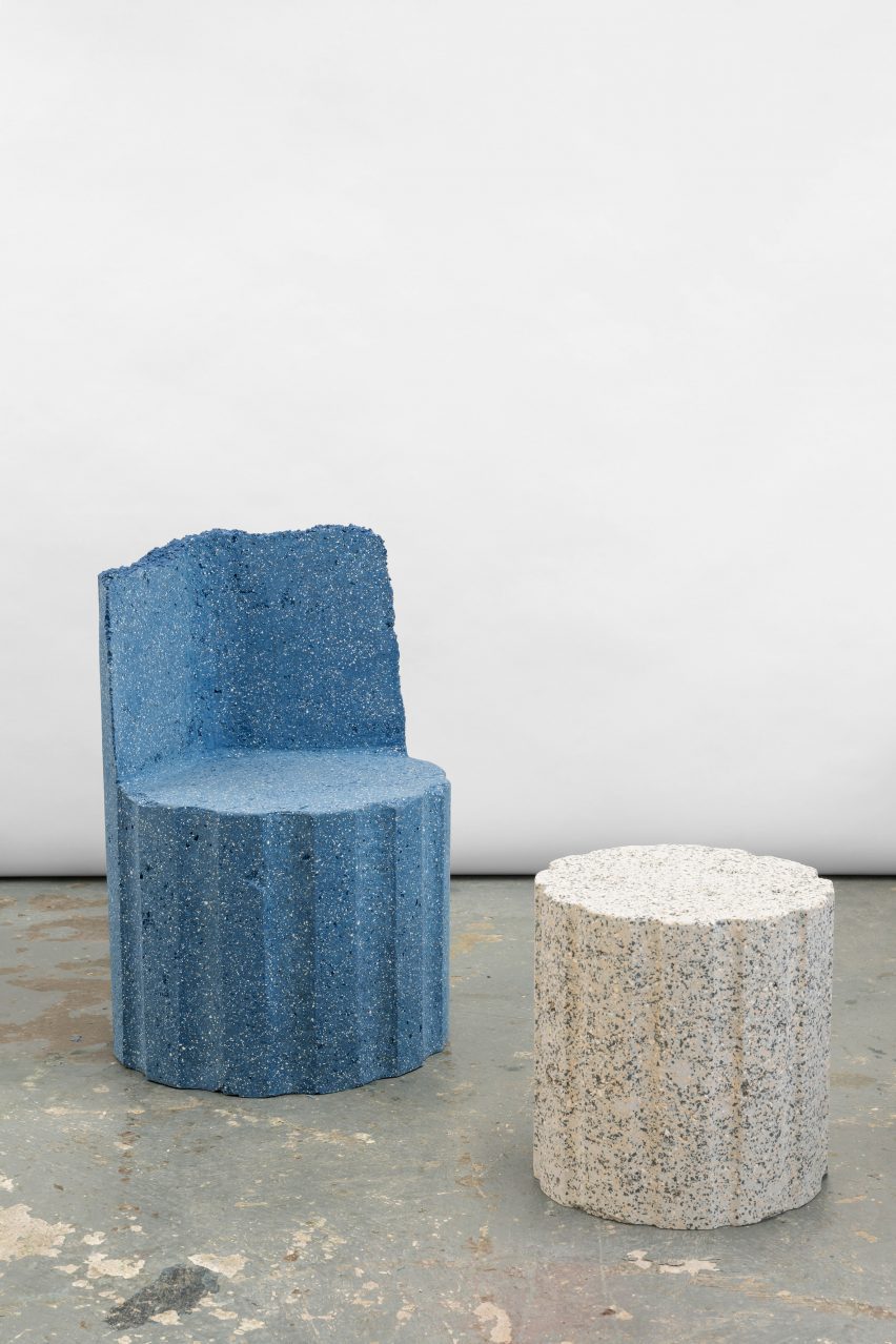 Photograph of two pieces from the collection, including a blue granite-looking armchair and a white granite-looking stool.
