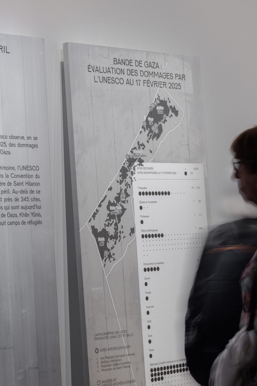 Photo of a person looking at a map of the Gaza Strip printed on a metal background in the Treasures Rescued from Gaza exhibition