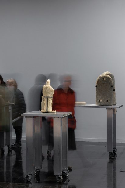 Photo of two ancient objects from the Gaza Strip on modern aluminium plinths as exhibition visitors blur around them