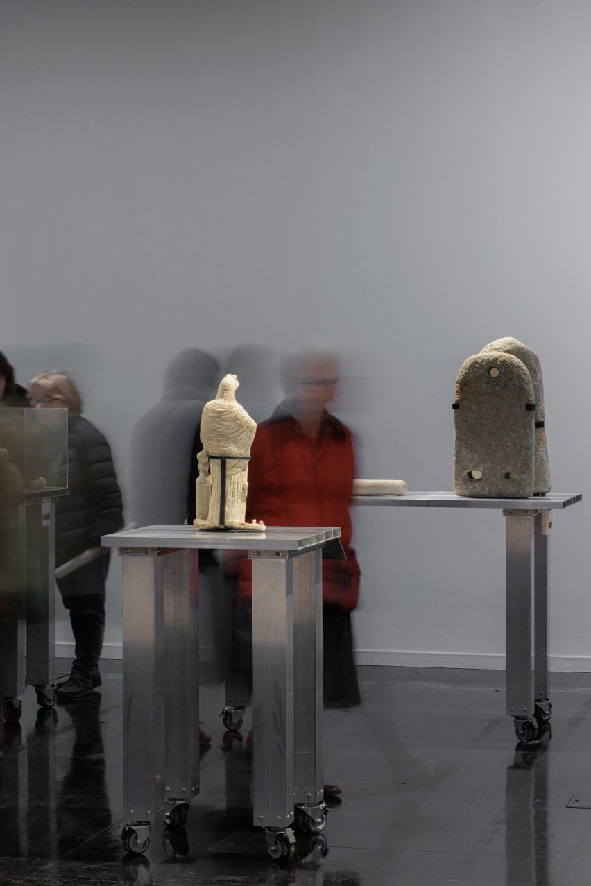 Photo of two ancient objects from the Gaza Strip on modern aluminium plinths as exhibition visitors blur around them