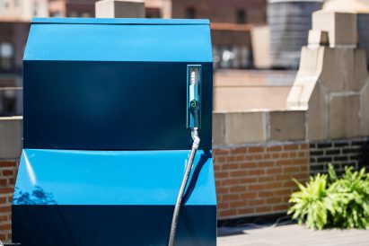 Photo of a side view of the Aircela air-to-fuel machine showing bright blue side panels and a petrol station-style hand pump