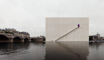 a visualisation of a beige square building by a river