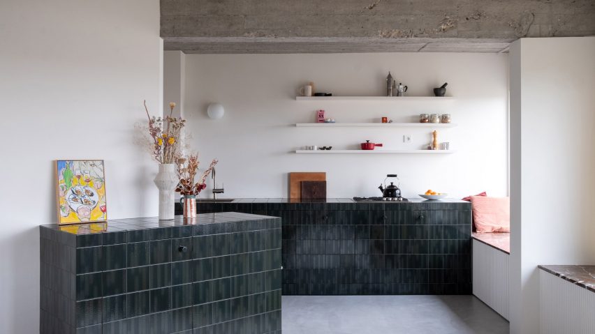 Kitchen with units clad in dark green and blue tiles
