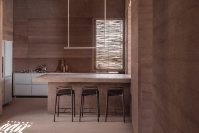 Metallic units in rammed-earth kitchen