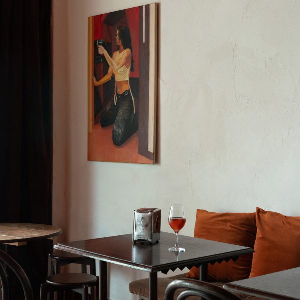 Bar interior with wooden seating, glass pendant light shades and painting on the wall
