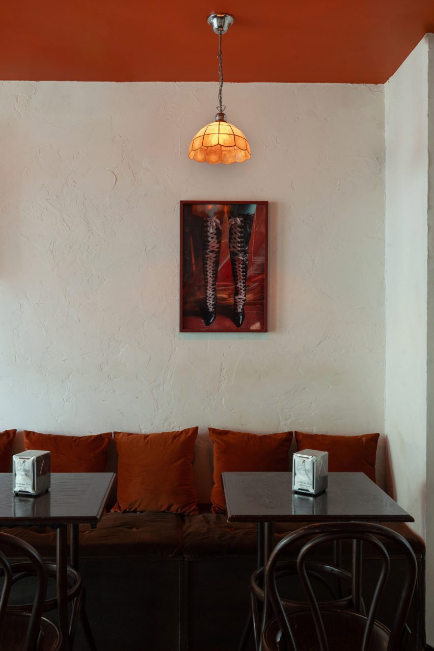 Bar interior with wooden seating, glass pendant light shades and painting on the wall