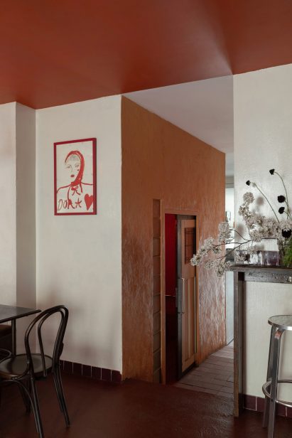 Bar interior with wooden seating, red ceiling and painting on the wall
