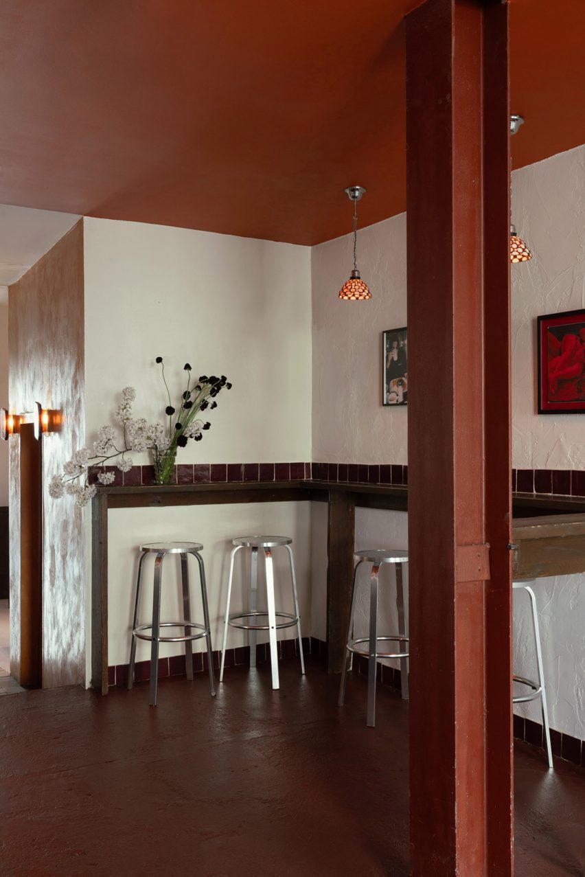 Bar interior with wooden seating, red ceiling and painting on the wall