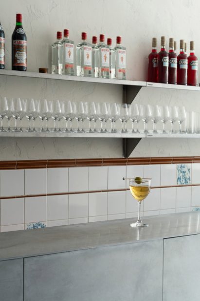 Bar interior with aluminium bar and metal shelving behind holding bottles and glasses