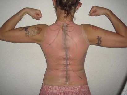 a photograph from behind of a person wearing a pink latex top