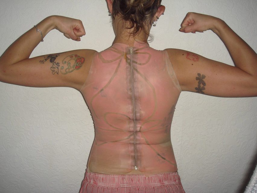 a photograph from behind of a person wearing a pink latex top