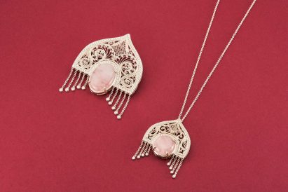 a photograph of silver jewellery pendants against a red backdrop