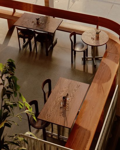 An aerial view over wooden tables arranged around a curve-cornered bench
