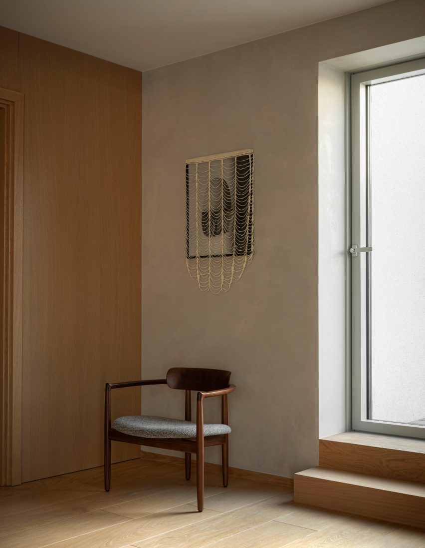 Wooden chair below contemporary artwork in hotel room