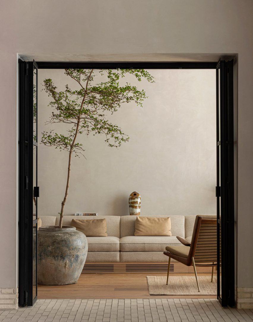 Lounge area with long white sofa and large ceramic pot