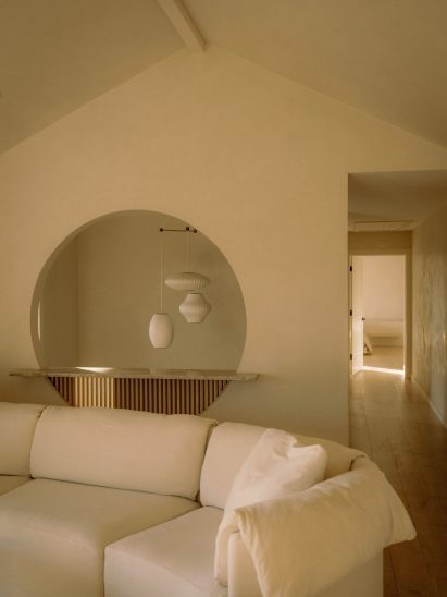 Circular opening with a view from an upstairs lounge to paper pendant lights in a stairwell