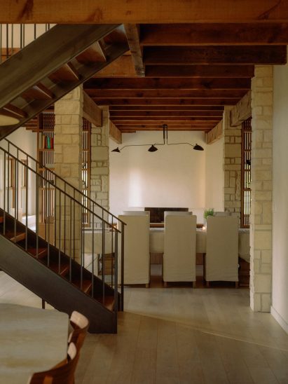 View past a stairwell on the left to a dining room with closed-back chairs