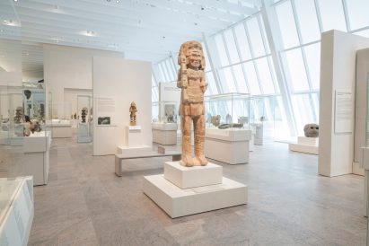 Stone works from the ancient Americas beside large slanted windows