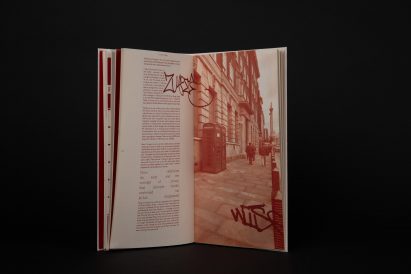 a photograph of a book in tones of red, against a black backdrop