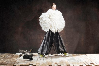 a photograph of a model wearing a large white garment and black trousers