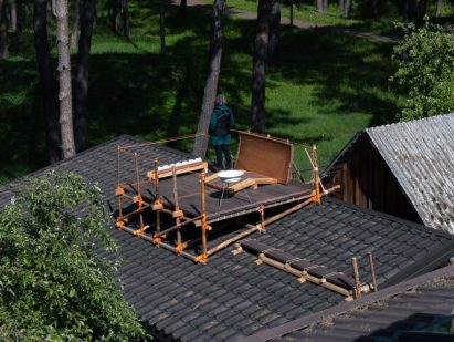 a photograph of a wooden structure on a roof, with a person standing on it