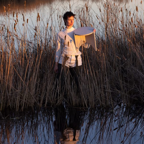 Photo of a person holding a wooden stool in marshlands