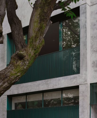 Detail of gray plaster and teal metalwork across the facade of a renovated 1940s building