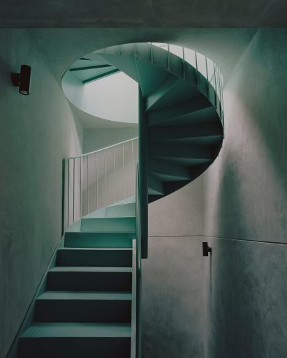 Teal staircase within a gray plaster vestibule