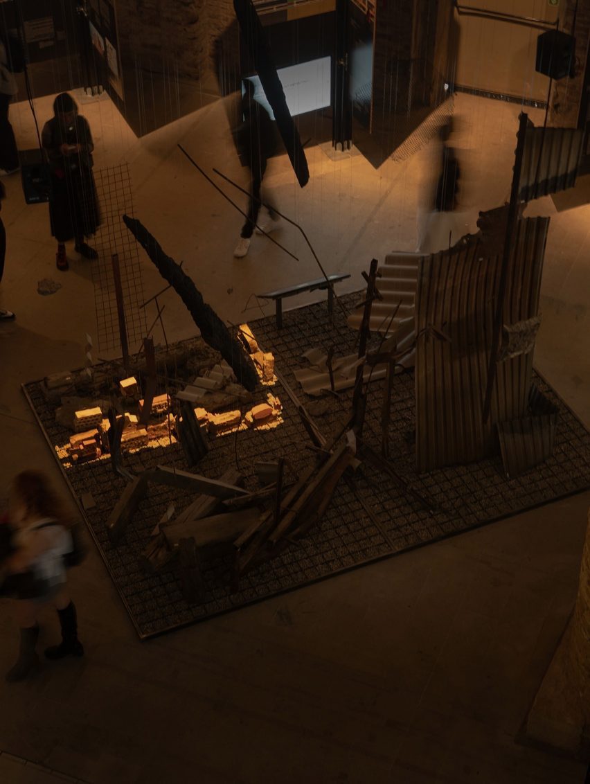 Photo of the Circularity on the Edge installation at the Venice Architecture Biennale 2025, showing materials arranged in a dark room with a laser projection lighting up one section of the display