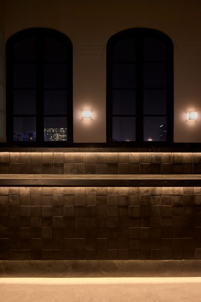 Cafe bar is fronted with wood tiles, seen at night