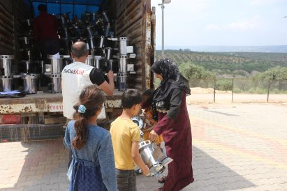 ReliefAid worker handing flat-packed cooking stoves to people out of a truck