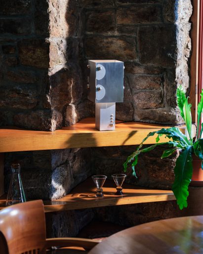 Metal lamp on top on an oak shelf in front of a stone wall