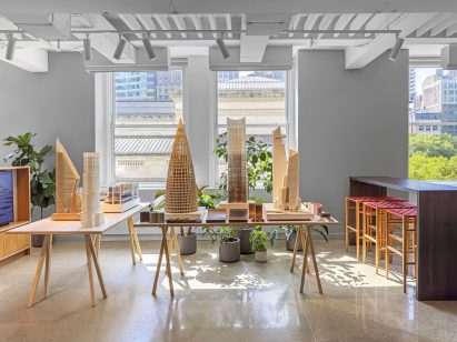 Series of wooden architectural models displayed on trestle tables