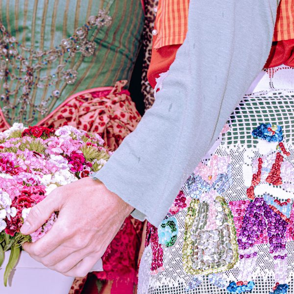 a cropped photograph of people wearing garments in tones of green, pink, red and white