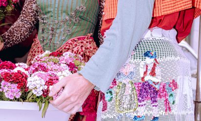 a cropped photograph of people wearing garments in tones of green, pink, red and white