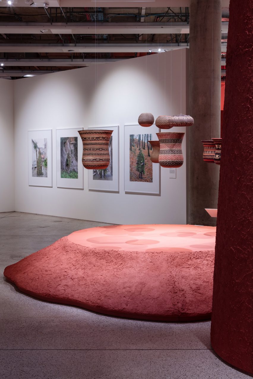 Photo of a clay mound with exhibits hanging above it in the More Than Human exhibition