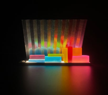 a photograph of an illuminated structure in tones of red, pink, yellow green and blue