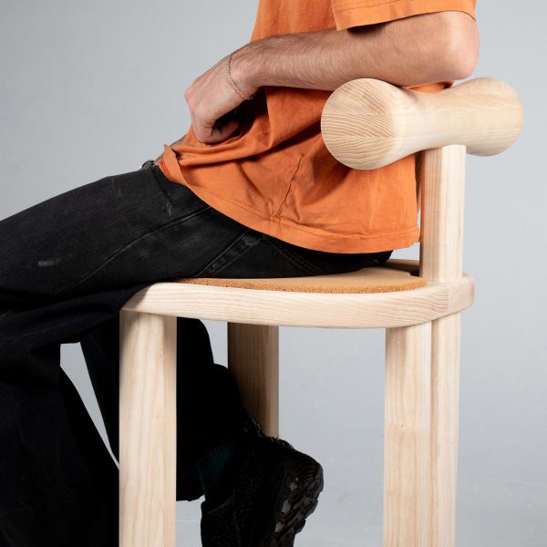 Person sitting on wooden bar stool made from light-coloured grained wood