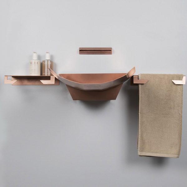 Rose gold-coloured bathroom products mounted on light grey wall