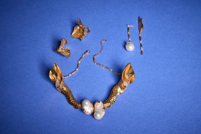 a photograph of jewellery laid against a blue surface