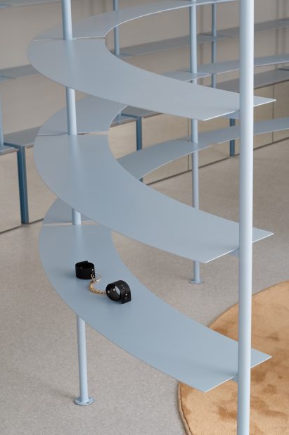 Leather handcuffs displayed on a baby-blue shelving unit