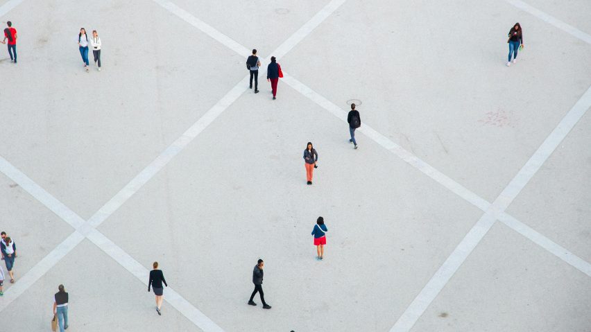 Aerial photo of people walking alone or in pairs or standing still in a vast concrete public space