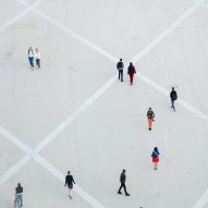 Aerial photo of people walking alone or in pairs or standing still in a vast concrete public space