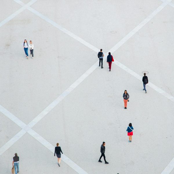 Aerial photo of people walking alone or in pairs or standing still in a vast concrete public space