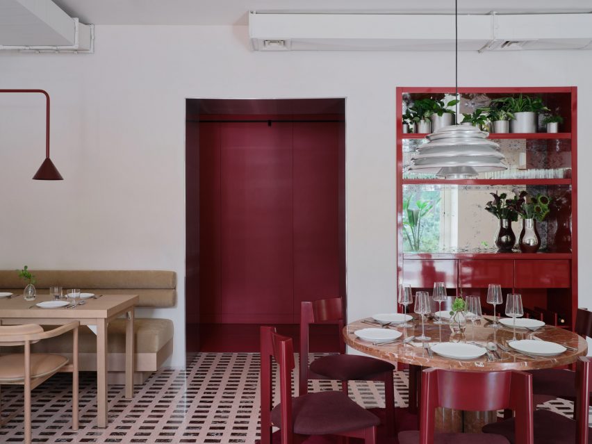 Red wall panels, drinks cabinet and chairs inside wine bar