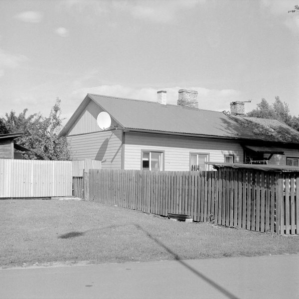 Greyscale photo showing a bungalow and fence in a residential area