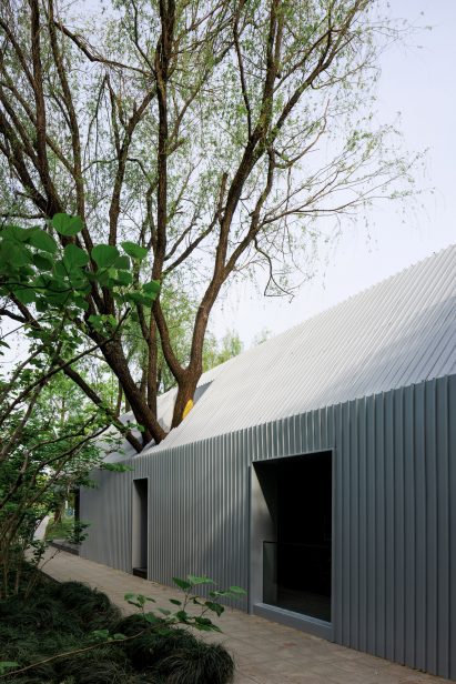 View of tree growing through The Lake House by Wutopia Lab