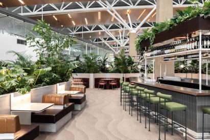 Airport lounge with bar and lounge seating surrounded by plants